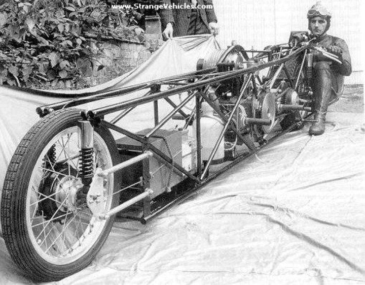 A historical lowriding motorcycle with the oddest driver seat position.